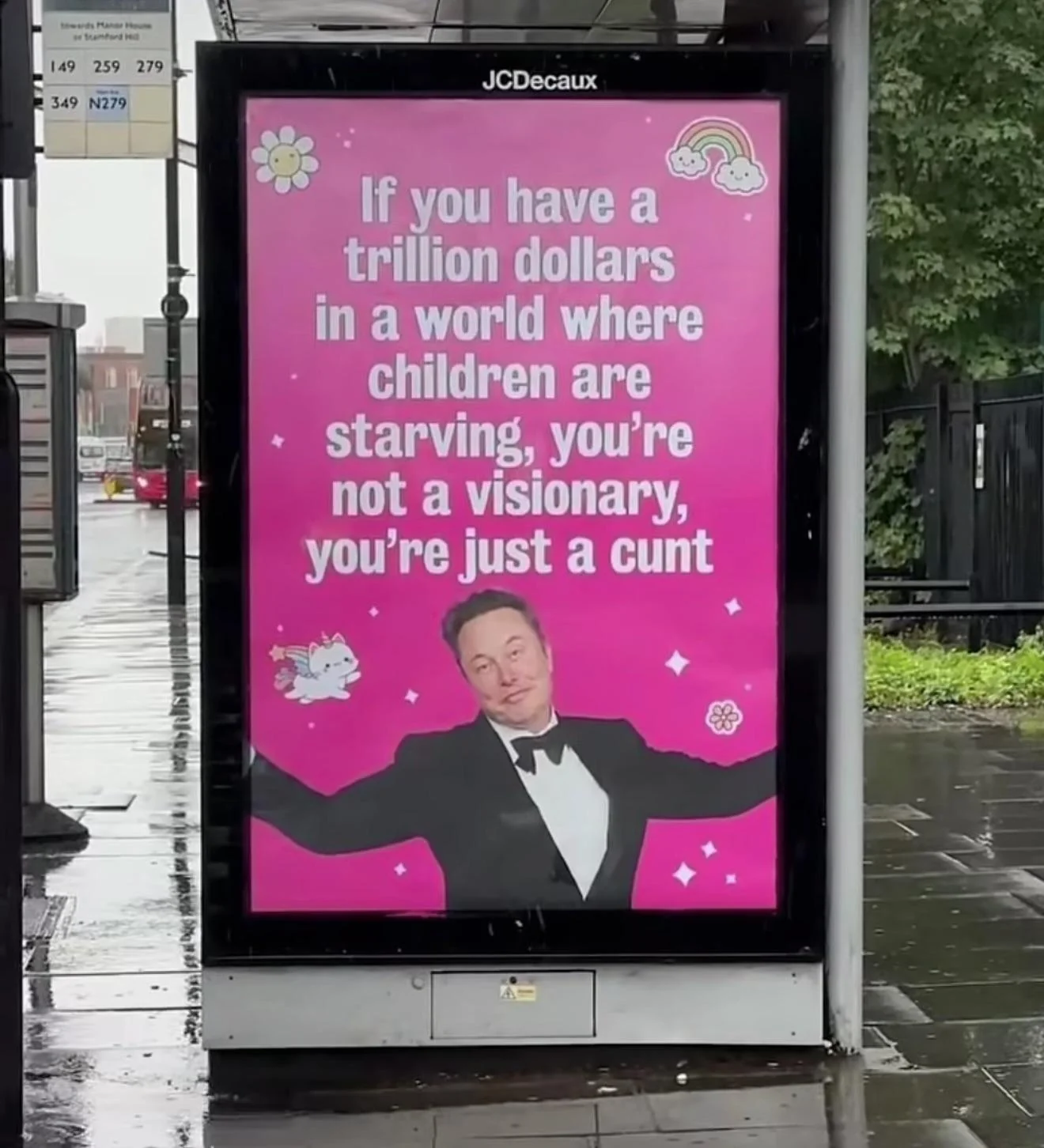 Bus-stop advert featuring a photo of Elon Musk with a smug expression. Text on the advert reads "If you have a trillion dollars in a world where children are starving, you're not a visionary, you're just a cunt."